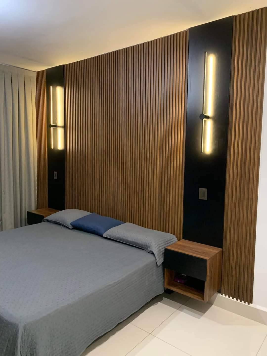 Panel WPC para cabecero con apliques de pared LED verticales en dormitorio