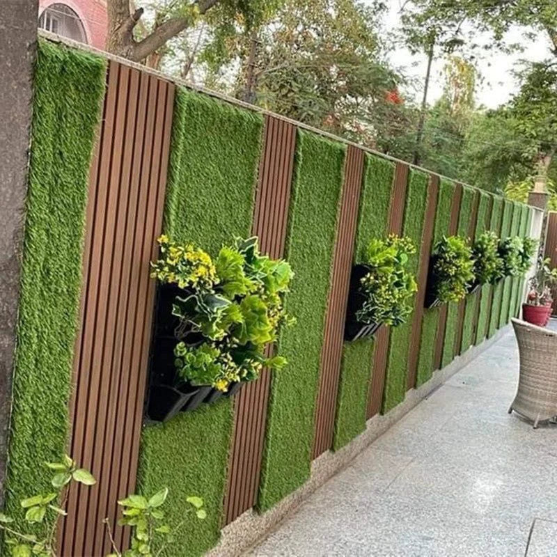 Cerramiento exterior decorado con listones WPC color madera, franjas de césped vertical y jardineras colgantes.