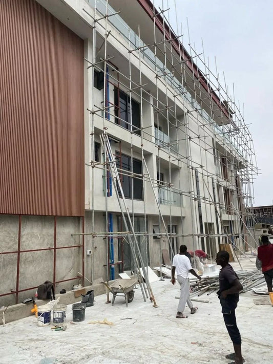 Edificio de varios pisos en construcción con paneles WPC color madera instalados en secciones verticales de la fachada.