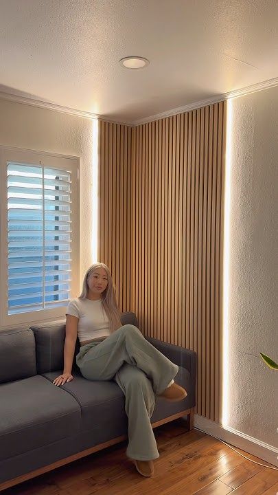 Paneles WPC para pared interior con iluminación LED vertical junto a sofá