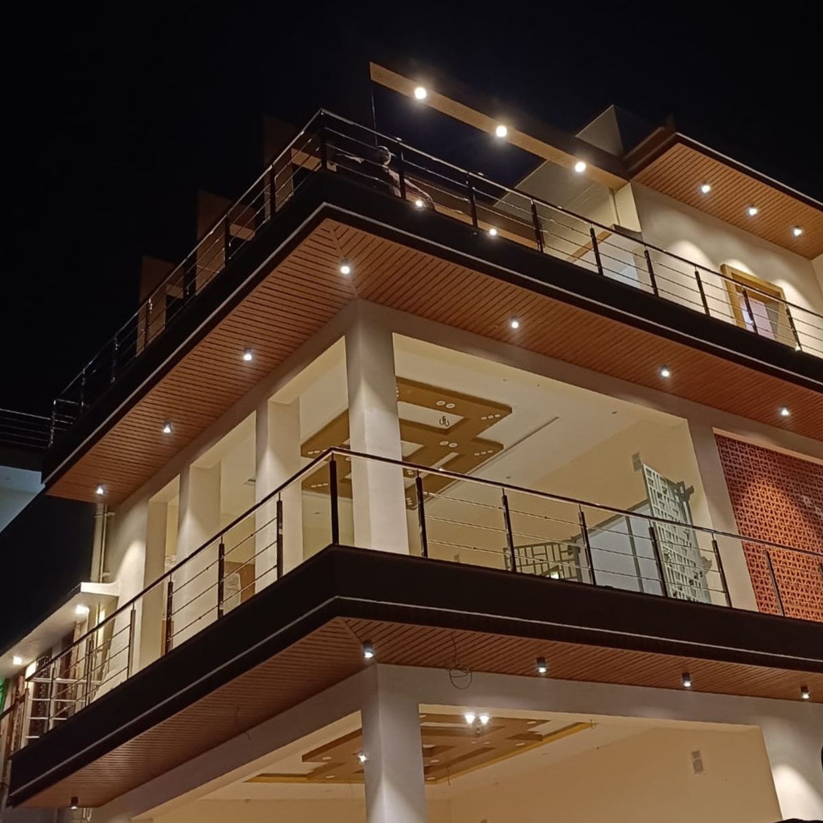 Cielo WPC tipo madera en fachada moderna de varios niveles con iluminación en Candelaria